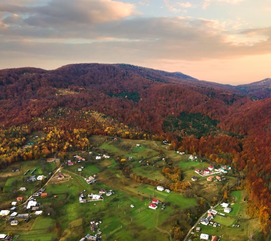 Aerial view of a rural village nestled between autumn-colored mountain hills, symbolizing the connection between landownership and diversified income opportunities.